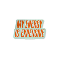 Vinyl sticker with glitter-style orange text reading “My Energy Is Expensive” on a mint background.