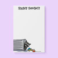 Trashy Thoughts raccoon notepad flat lay — funny trash panda notepad by indie artist MangoIllustrated