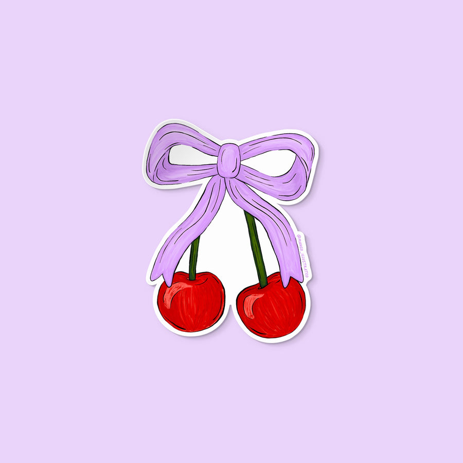 Vinyl sticker of two red cherries tied together with a lavender bow illustration.