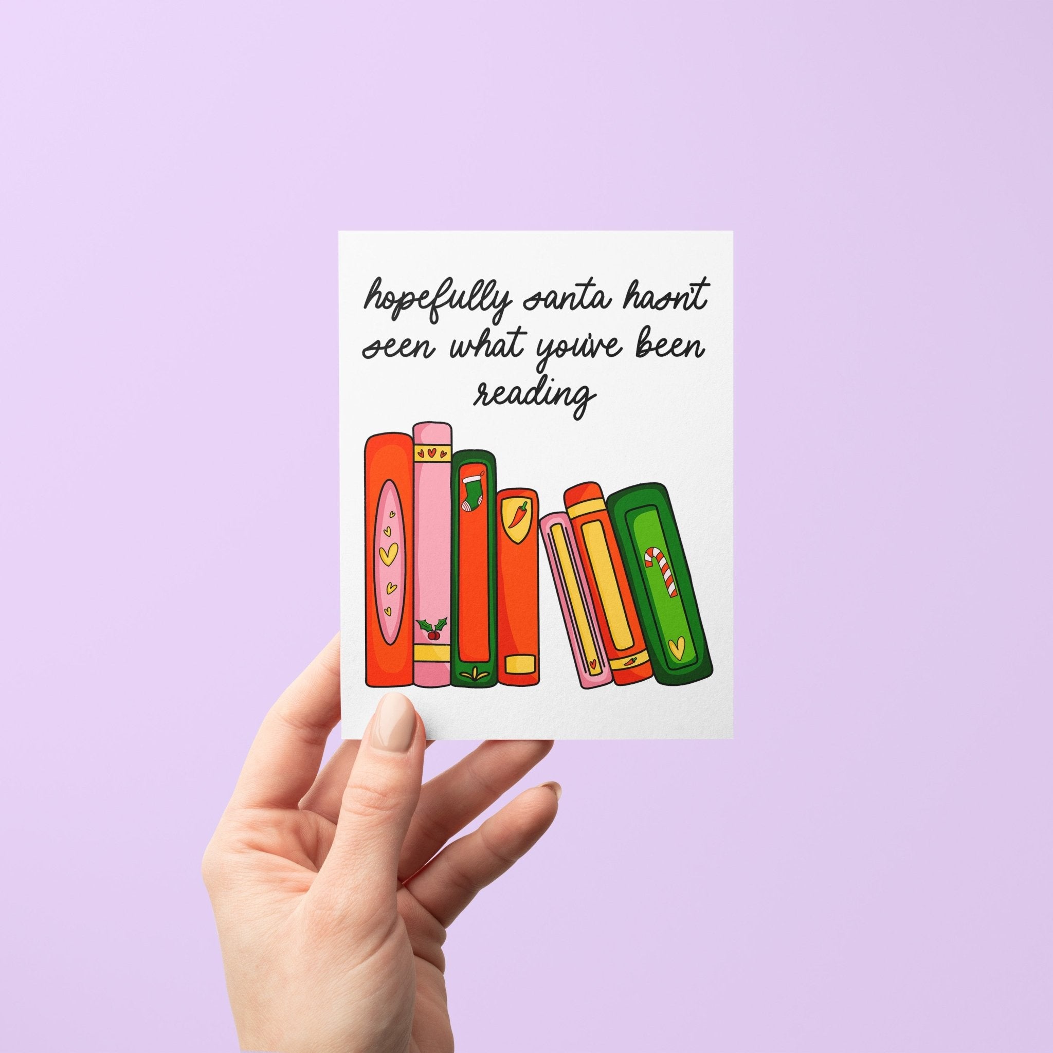 Funny holiday card with illustrated books and the message “Hopefully Santa hasn’t seen what you’ve been reading,” featuring festive book spines in red, green, pink, and orange.