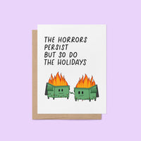 Humorous holiday card with two flaming dumpster characters holding hands, decorated with string lights, and the text “The horrors persist but so do the holidays.”