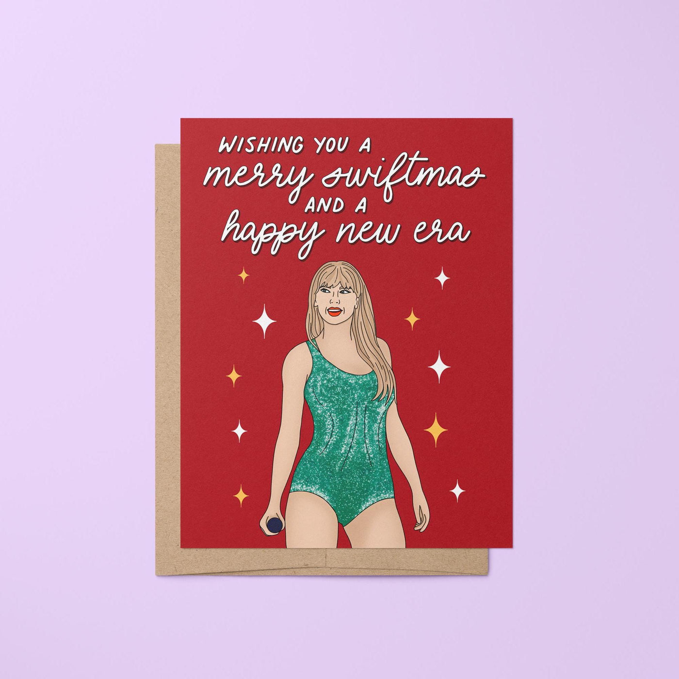 This card features an illustration of Tay in a green version of her Lover era Eras Tour bodysuit surrounded by stars. The greeting in mixed script and sans serif hand lettering reads &quot;wishing you a merry swiftmas and a happy new era.&quot;