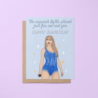 This Long Live Swiftie Hanukkah card features an illustration of Tay in a blue version of her Lover era Eras Tour bodysuit surrounded by stars against a light blue background. The greeting reads &quot;the menorah lights shined just for me and you.&quot;