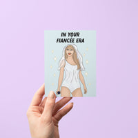 Engagement card with the phrase “In Your Fiancée Era” featuring an illustration of a woman in a sparkling outfit with a bridal veil and microphone.
