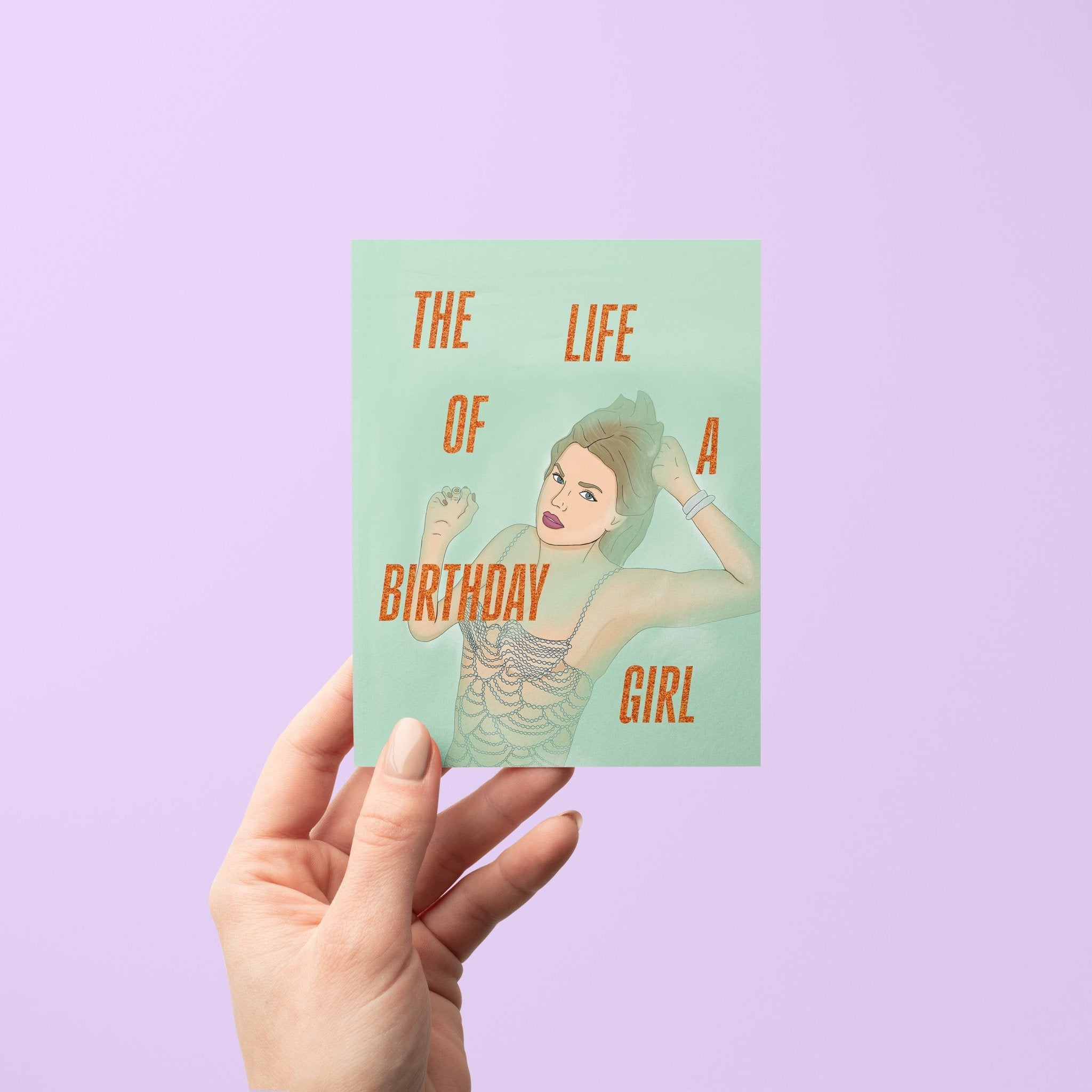 Taylor Swift-inspired birthday card titled “The Life of a Birthday Girl” featuring an illustrated glamorous woman in a sparkling, beaded-style outfit on a mint green background, paired with a kraft envelope.