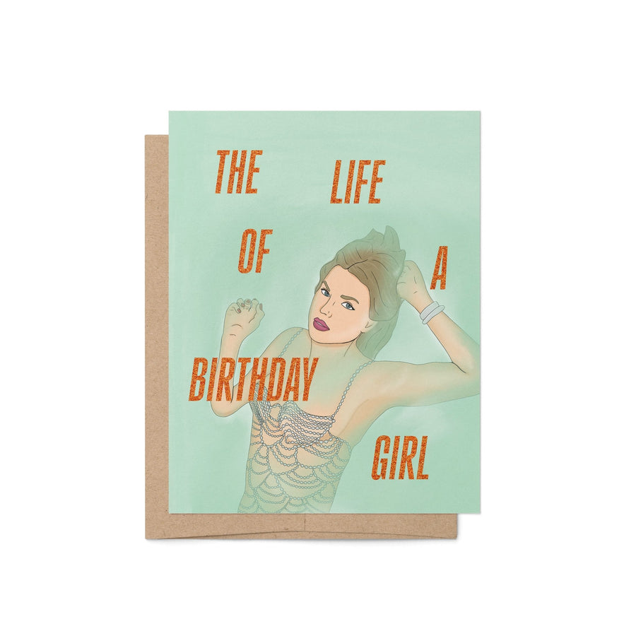 Taylor Swift-inspired birthday card titled “The Life of a Birthday Girl” featuring an illustrated glamorous woman in a sparkling, beaded-style outfit on a mint green background, paired with a kraft envelope.